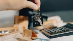Close-up of a hand holding keys over euros and calculator, symbolizing real estate purchase.
